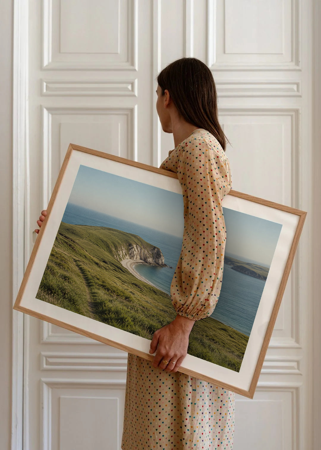 Poster in een interieur: Panorama van een groene kaap met een wandelpad, lichte kliffen en een beschutte blauwe baai