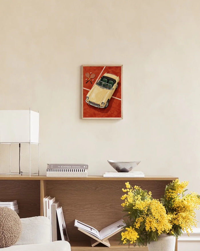 Poster in een interieur: Geschilderde crèmekleurige roadster met groene stoelen, houten rackets en tennisballen op rood gravel