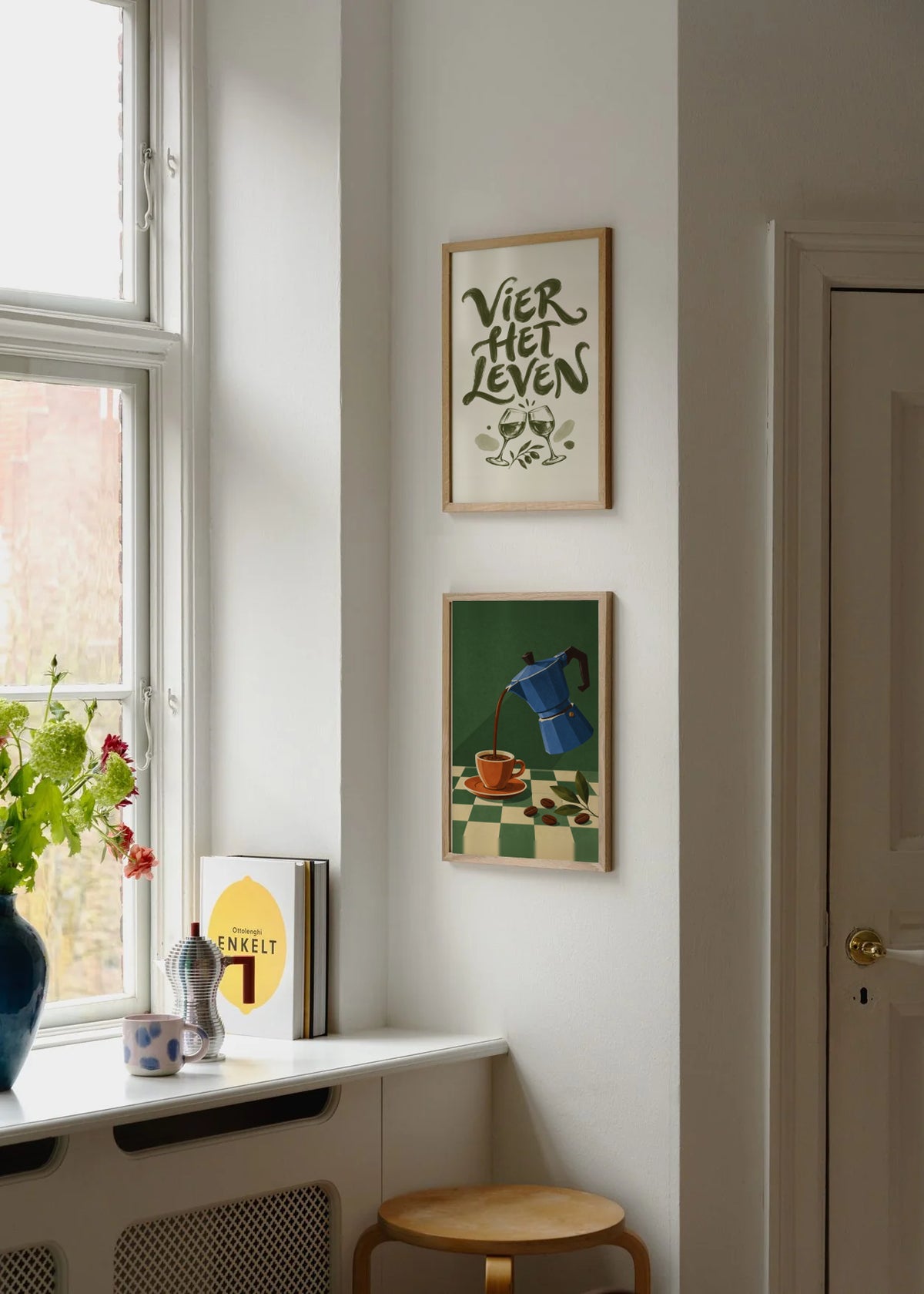 Poster in een interieur: Olijfgroene tekst VIER HET LEVEN boven twee klinkende wijnglazen en bladeren op crème